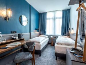 吕贝克Mercure Hotel Luebeck City Center的酒店客房配有两张床和一张书桌