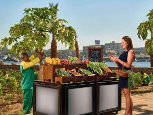 阿斯旺阿斯旺瑞享酒店的站在水果和蔬菜站旁的女人