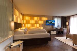 罗登戈Hotel Schönblick的一间卧室配有一张大床和电视