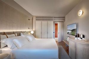 奇亚Veridia Resort Sardinia, a member of Radisson Individuals的卧室配有一张白色大床和一张书桌