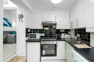 伦敦Islington Hideout的厨房配有白色橱柜和黑色瓷砖