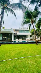 Xuyên MộcBiệt thự 5PN Resort Sanctuary HỒ Tràm ll Bãi biển riêng ll hồ bơi BBQ的庭院前有棕榈树的建筑