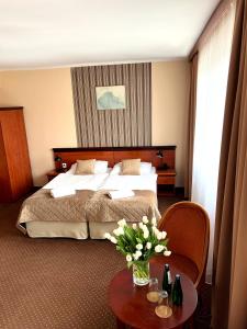 卡托维兹扎伦泽酒店的配有床和鲜花桌的酒店客房