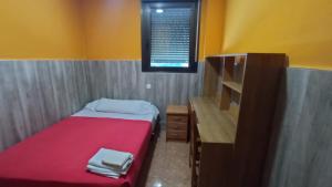 瓜达拉哈拉圣马科斯2号旅馆的一间小卧室,配有红色的床和一张书桌