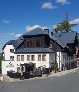 卡尔帕奇Hotel Kolorowa的一条白色的街道上,有黑色屋顶