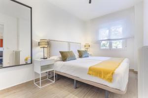 马德里Metropolitano en Madrid的白色卧室配有一张带黄色毯子的大床