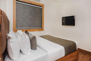 孟买FabHotel Airport Palace的一间卧室设有一张床和一个带电视的窗户。