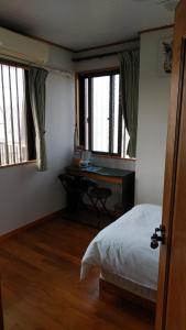 那霸Hou heights - Vacation STAY 63956v的一间卧室配有一张床、一张书桌和两个窗户。