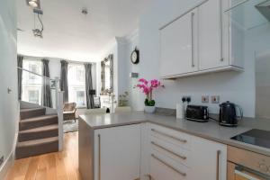 伦敦GuestReady - Stunning Covent Garden 2BR Duplex的厨房配有白色橱柜和粉红色的花朵