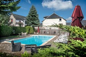 Albaret-Sainte-Marie白岩酒店的一个带椅子的游泳池以及一座房子