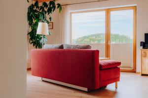 茨维泽尔Lindenhaus的客厅设有一张红色的沙发,配有大窗户