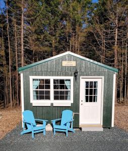 Bass HarborLighthouse Cabins Maine的前面有两把蓝色椅子的绿色棚子