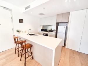 悉尼Cozy Apartment at St Leonard的白色的厨房,配有一个柜台和两个凳子