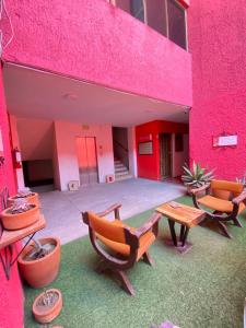 瓜达拉哈拉Hotel Flamingos的粉红色的建筑,配有桌椅和庭院