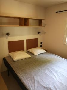 Lansargues乐夫都罗伊露营地假日公园的一间卧室配有一张带两个枕头的床