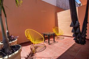 巴亚尔塔港Hotel Tropicus Boutique的庭院里设有3把黄色椅子和一张桌子