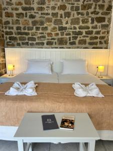 阿基欧斯尼古拉斯Naiades Almiros Hotel的一张带白色床单的床和一张带书籍的桌子