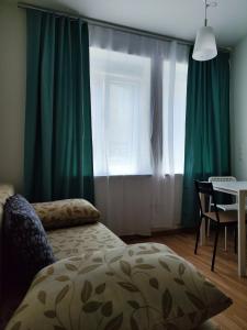 维也纳Hostel&ApartServices Viennna The Tidy Apartment的一间卧室配有绿色窗帘、桌子和床