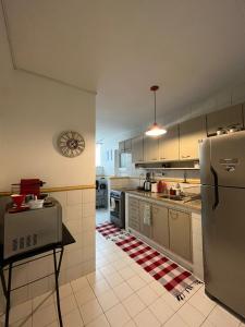 里约热内卢Apartamento Aconchegante na Zona Sul, Botafogo Rj的厨房配有冰箱和墙上的时钟