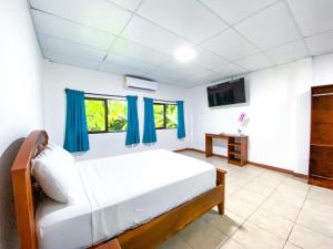 El MajahualMajahual Resort的一间卧室配有一张带蓝色窗帘的床和电视。