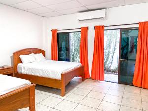 El MajahualMajahual Resort的一间卧室配有两张床和橙色窗帘