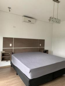 瓜鲁雅Casa em Guarujá-Jardim Acapulco的一间卧室设有一张床和白色的墙壁