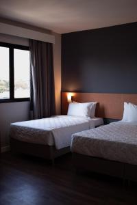 普鲁登特总统城Comfort Hotel Presidente Prudente的酒店客房设有两张床和窗户。