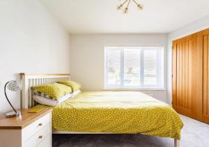切森特Whiteclouds的一间卧室配有一张带黄色床单的床和一扇窗户。