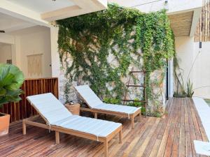 埃斯孔迪多港Casa Ita Surf - Adults Only的天井上设有两把椅子,墙壁上覆盖着常春藤