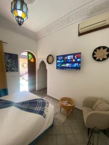 马拉喀什RIAD KECHMARA的一间卧室配有一张床、一把椅子和电视。