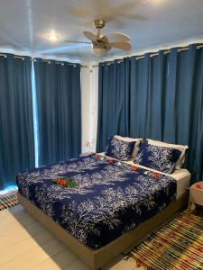 帕皮提A TOMO MAI Homestay的一间卧室配有蓝色窗帘和一张鲜花床