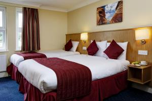 伦敦贝斯特韦斯特伦敦海布里酒店的酒店客房,配有两张带红色床单的床