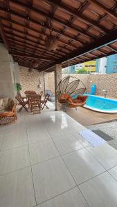 若昂佩索阿Casa de Férias á 400m pra Praia de Cabo Branco的庭院设有游泳池、桌子和椅子。