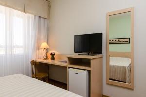 亚瓜龙Hotel Sinuelo的一间卧室配有一张桌子、一台电视和一张床