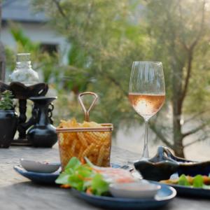 苏梅岛Moorea Boutique Resort Samui的坐在桌子上一边品尝葡萄酒,一边享用食物