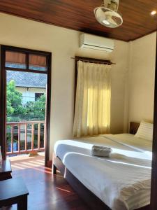 琅勃拉邦Tingkham Guesthouse的一间卧室配有一张床,阳台设有窗户