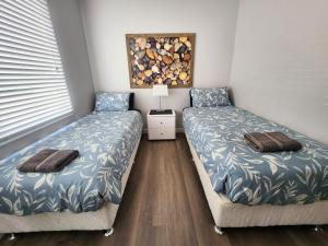 朱里恩湾Unit 51 Seafront Estate的一间卧室配有两张床和一张带台灯的桌子