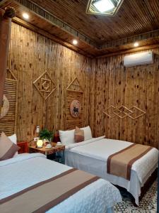 宁平Tam Coc Village Bungalow的一间卧室设有两张床和木墙