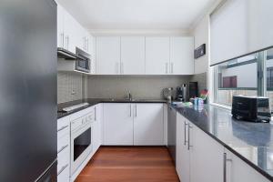 悉尼Perfect Pyrmont penthouse with Sydney Tower View的厨房配有白色橱柜和黑色台面