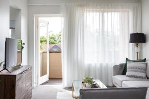 悉尼Sunny Apartment in Quiet and Green Neighbourhood的带沙发和大窗户的客厅