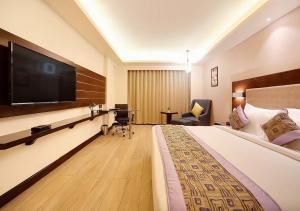 新德里Balwood Suites Near Delhi Airport的一间酒店客房,配有一张大床和一台平面电视