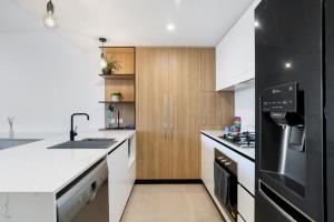 布里斯班Convenient 2-Bed Apartment with Panoramic Views的厨房配有白色台面和木制橱柜