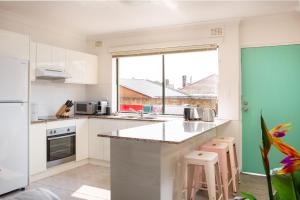 悉尼Cosy 2-Bed Apartment in the Heart of Strathfield的一间厨房,配有白色的橱柜和大窗户
