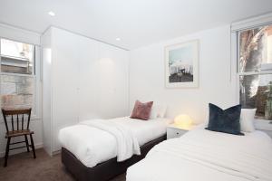 悉尼Spacious 3-Bed Family House with Courtyard的白色墙壁客房的两张床