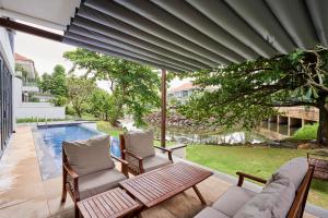 岘港Ocean Sunny Villas Da Nang的一个带沙发和椅子的庭院和一个游泳池