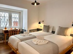 里斯本262 Baixa Guesthouse的配有书桌和窗户的客房内的两张床