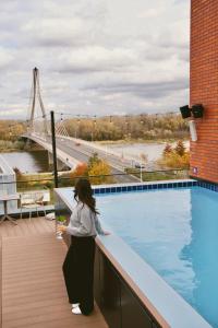 华沙Barceló Warsaw Powiśle的站在游泳池旁阳台的女人