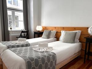 里斯本262 Baixa Guesthouse的带2扇窗户的客房内的2张床