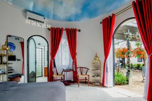 Phú ThạnhTrulli Villa Homestay Đà Lạt的一间设有红色窗帘和桌椅的房间