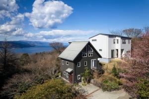 伊东Oceanic House TAMATEBAKO的享有高山上房屋的空中美景和湖景